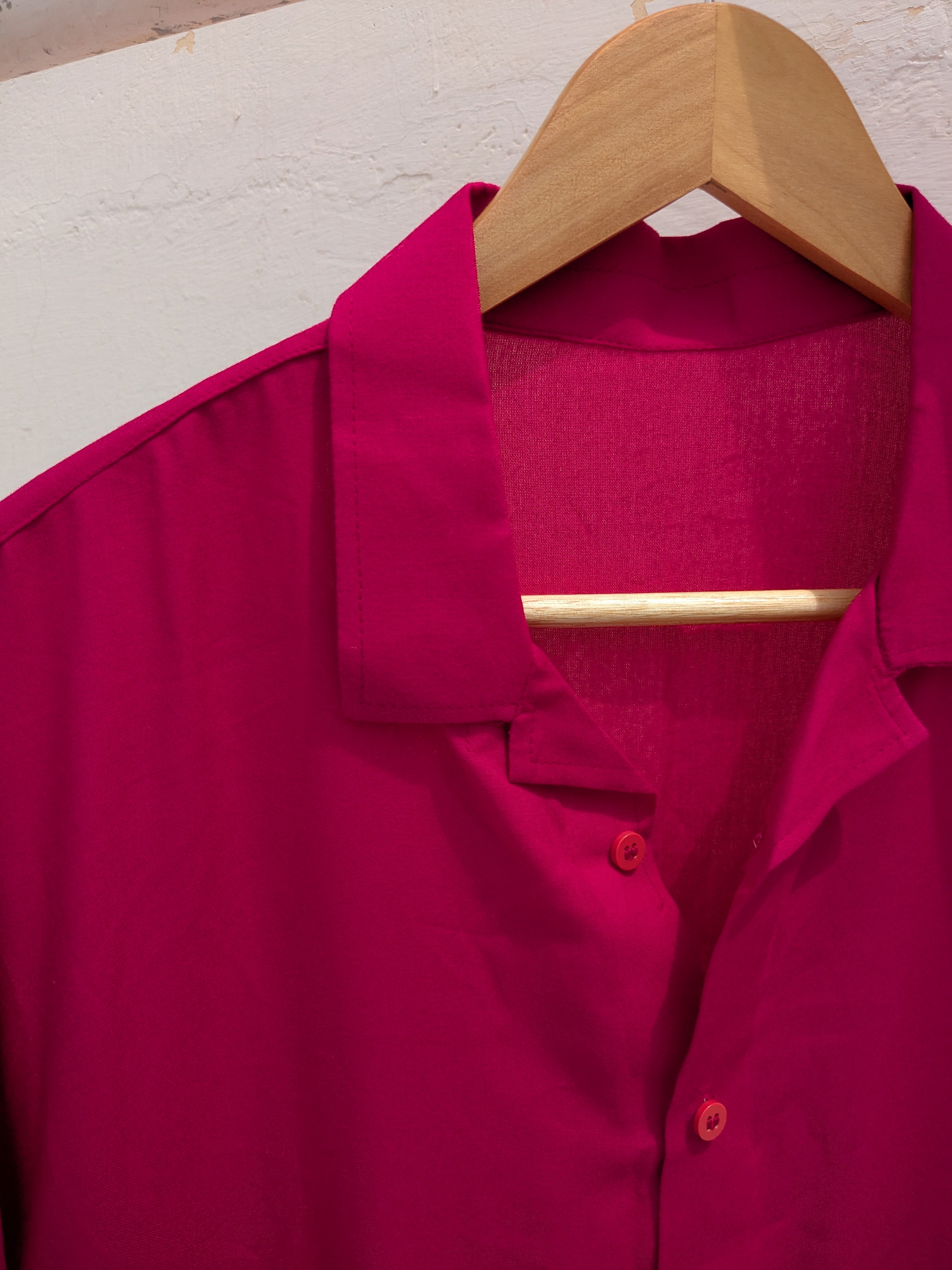 Pink shirt on a wooden hanger against a light background
